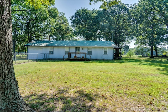 rear view of property featuring fence, metal roof, and a yard