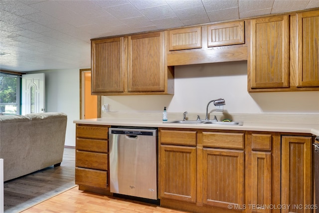 kitchen with light wood finished floors, light countertops, open floor plan, a sink, and dishwasher