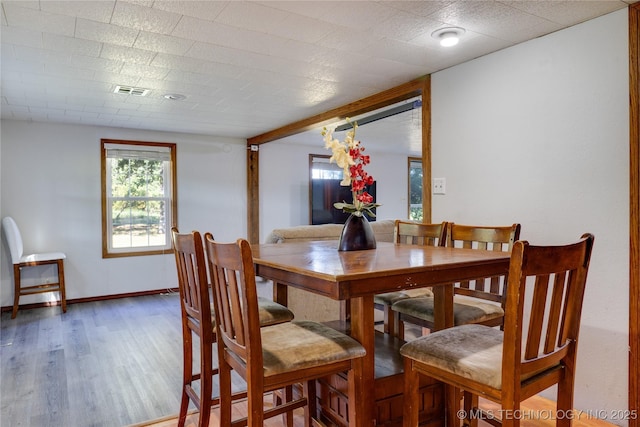 dining space featuring visible vents, baseboards, and wood finished floors