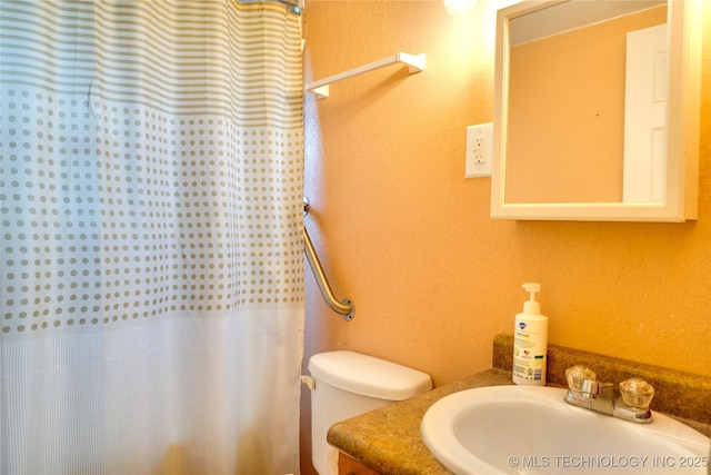 full bath featuring toilet, curtained shower, vanity, and a textured wall