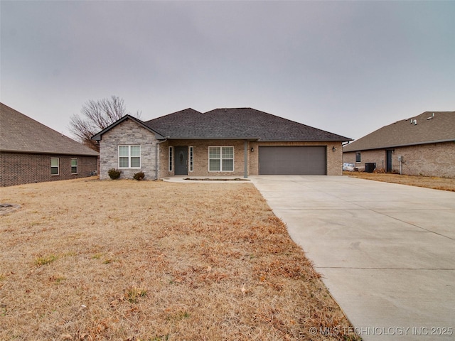 single story home featuring driveway, roof with shingles, an attached garage, a front yard, and brick siding