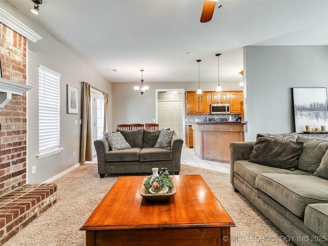 living room with light carpet, ceiling fan with notable chandelier, light tile patterned flooring, and baseboards