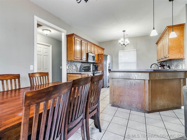 kitchen featuring appliances with stainless steel finishes, a notable chandelier, backsplash, and light tile patterned floors