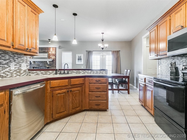 kitchen featuring light tile patterned floors, brown cabinetry, a peninsula, stainless steel appliances, and a sink