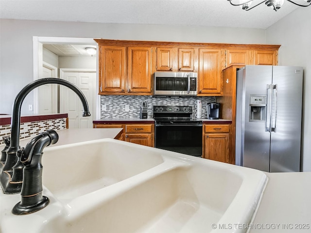 kitchen featuring appliances with stainless steel finishes, light countertops, brown cabinetry, and tasteful backsplash