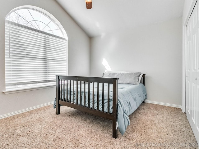 bedroom with baseboards, a ceiling fan, carpet, vaulted ceiling, and a closet