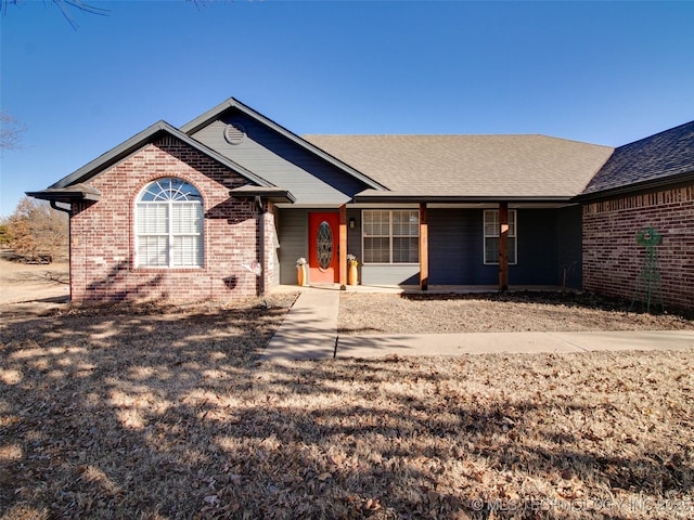 ranch-style home featuring a shingled roof and brick siding