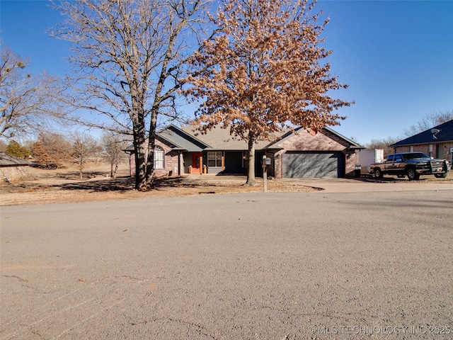 view of front of property featuring a garage, brick siding, and driveway