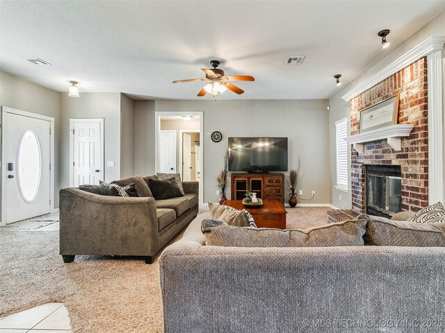 carpeted living area featuring visible vents, a fireplace, baseboards, and ceiling fan