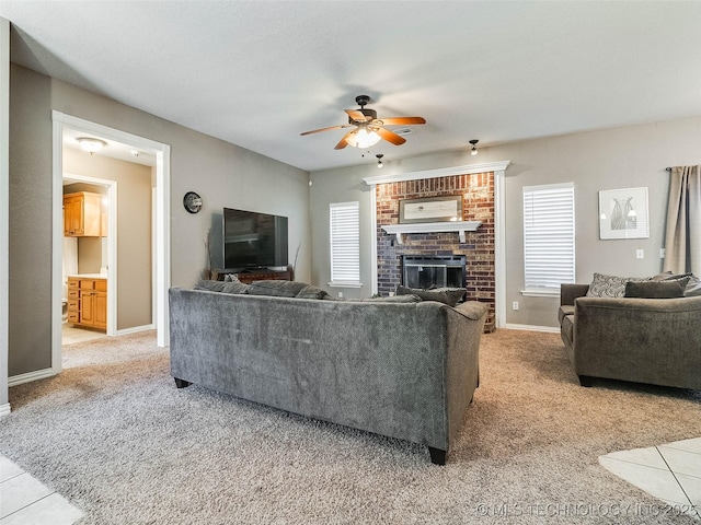 living room featuring a brick fireplace, baseboards, a ceiling fan, and light colored carpet