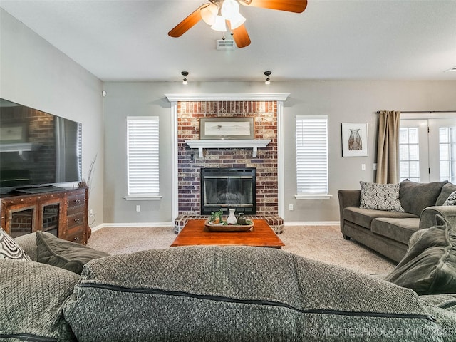 living room with carpet floors, visible vents, a ceiling fan, a brick fireplace, and baseboards