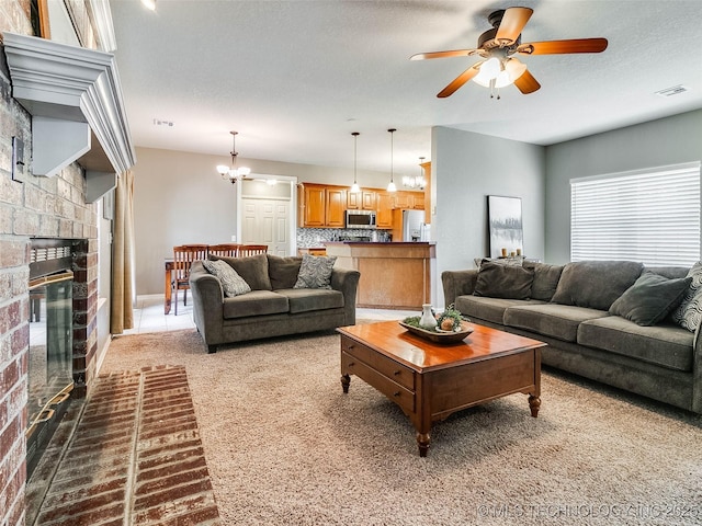 living area with a textured ceiling, ceiling fan with notable chandelier, carpet floors, visible vents, and a glass covered fireplace