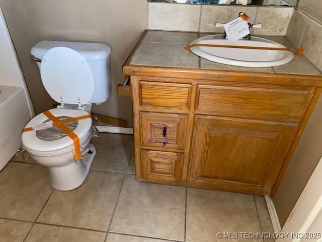 full bathroom with a tub to relax in, tile patterned flooring, vanity, and toilet