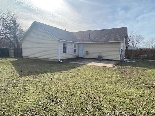 back of property featuring fence, central AC unit, and a lawn