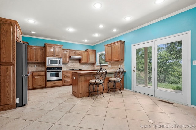 1474 S 271st W Ave, Sand Springs, OK 74063 - kitchen with stainless steel appliances, under cabinet range hood, a peninsula, ornamental molding, and decorative backsplash