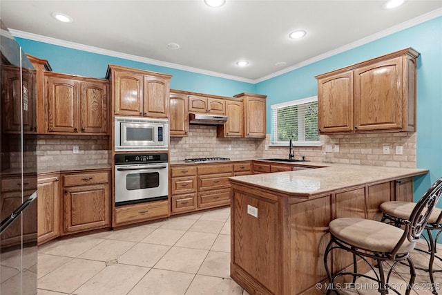 1474 S 271st W Ave, Sand Springs, OK 74063 - kitchen with appliances with stainless steel finishes, a peninsula, a kitchen bar, backsplash, and recessed lighting