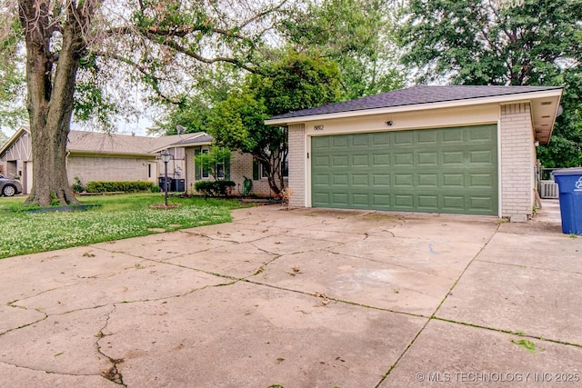 view of front of property featuring a garage, a front yard, brick siding, and an outbuilding