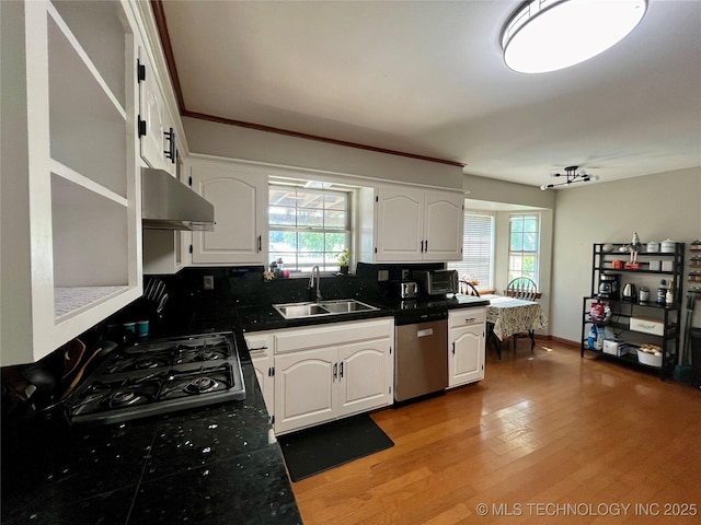 kitchen featuring dark countertops, white cabinetry, a sink, dishwasher, and under cabinet range hood