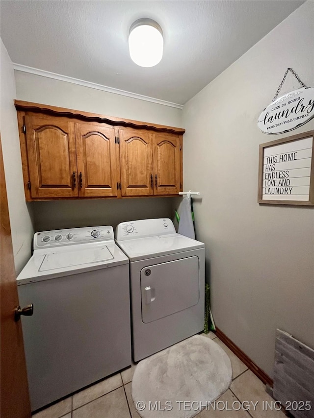 clothes washing area featuring light tile patterned floors, washing machine and clothes dryer, cabinet space, and baseboards