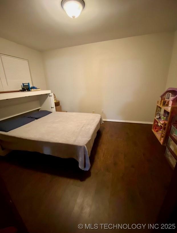 bedroom with dark wood-style floors and baseboards