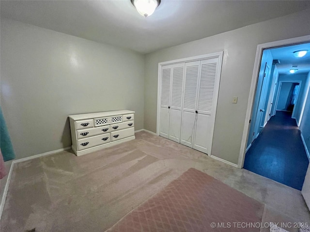 unfurnished bedroom with carpet, a closet, and baseboards