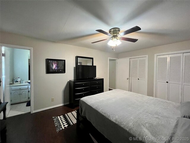 bedroom with ensuite bathroom, ceiling fan, dark wood-style flooring, baseboards, and two closets