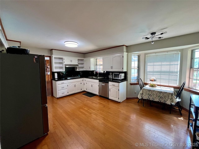 kitchen with light wood finished floors, open shelves, stainless steel appliances, dark countertops, and white cabinets