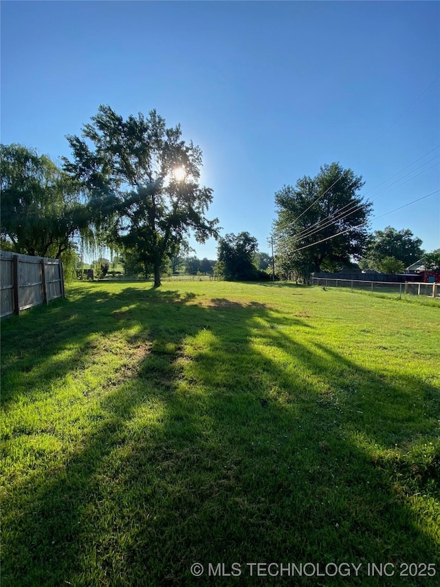 view of yard with fence and a rural view