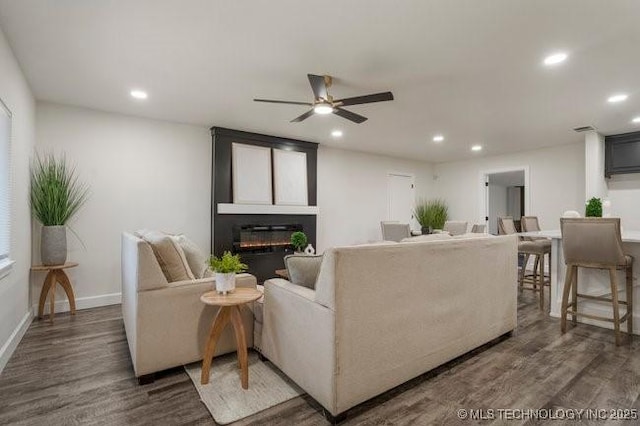 living area with a large fireplace, baseboards, wood finished floors, and recessed lighting