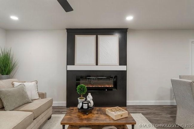 living room with recessed lighting, baseboards, wood finished floors, and a glass covered fireplace