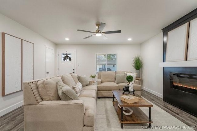 living room with a glass covered fireplace, recessed lighting, baseboards, and wood finished floors