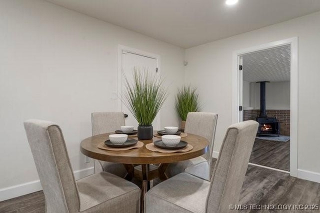 dining area with a wood stove, baseboards, and wood finished floors