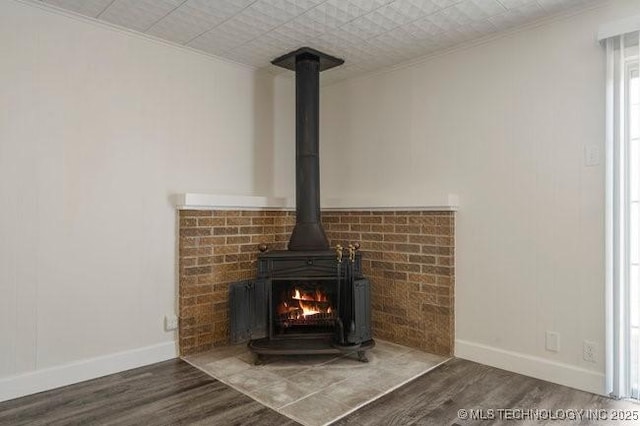 details featuring a wood stove, baseboards, and wood finished floors