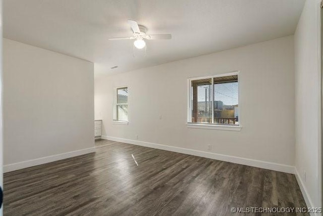 unfurnished room with a healthy amount of sunlight, baseboards, and dark wood finished floors