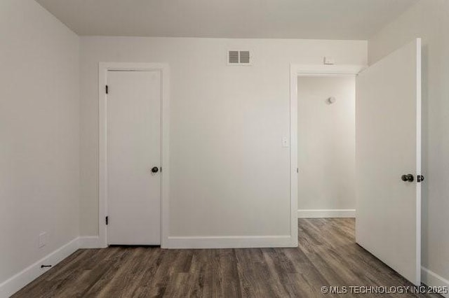 spare room featuring wood finished floors, visible vents, and baseboards