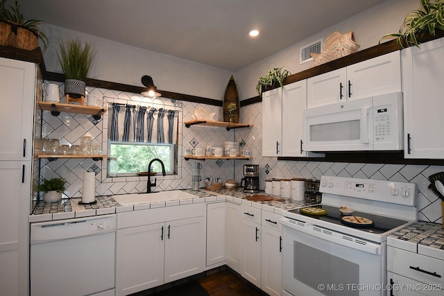 kitchen with white appliances, tile counters, open shelves, and a sink