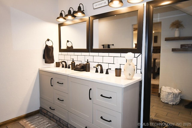 full bath with double vanity, baseboards, decorative backsplash, and a sink