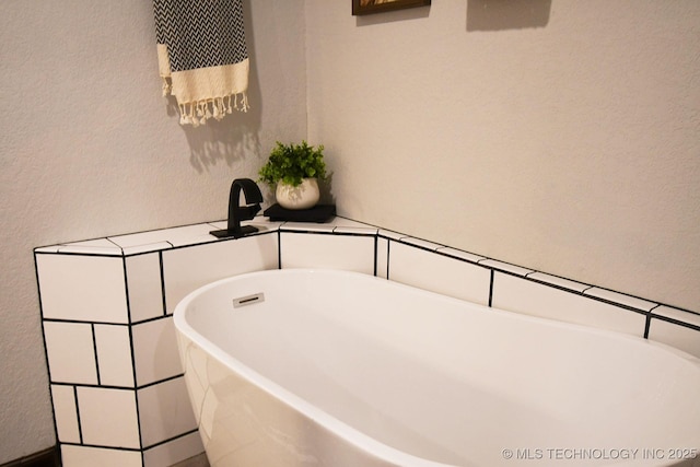 full bathroom featuring a soaking tub and a textured wall