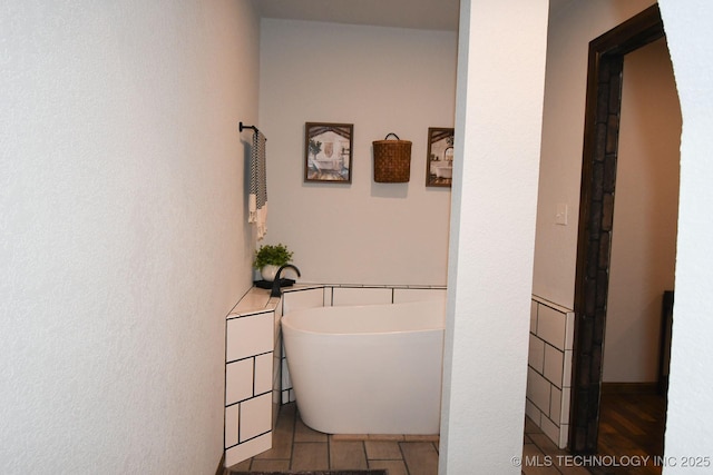 bathroom featuring a freestanding tub and tile patterned flooring