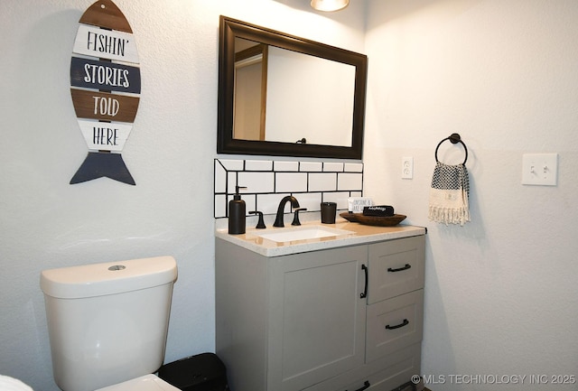 bathroom featuring toilet, vanity, and decorative backsplash