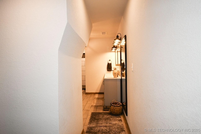 hallway with visible vents, baseboards, and wood finished floors