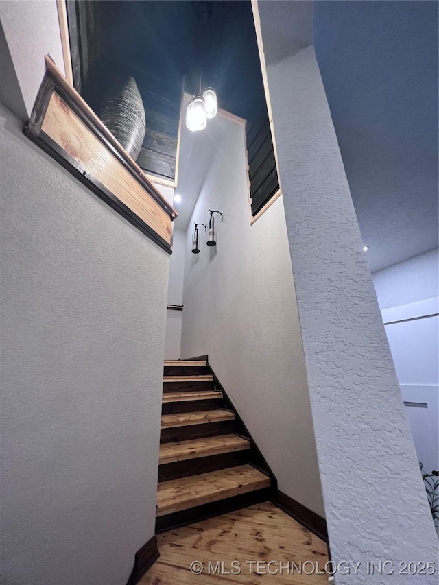 stairs featuring a textured wall and wood finished floors