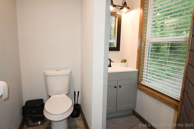 bathroom with toilet, baseboards, and vanity