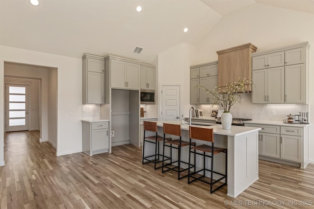 kitchen with built in microwave, light wood finished floors, and gray cabinetry