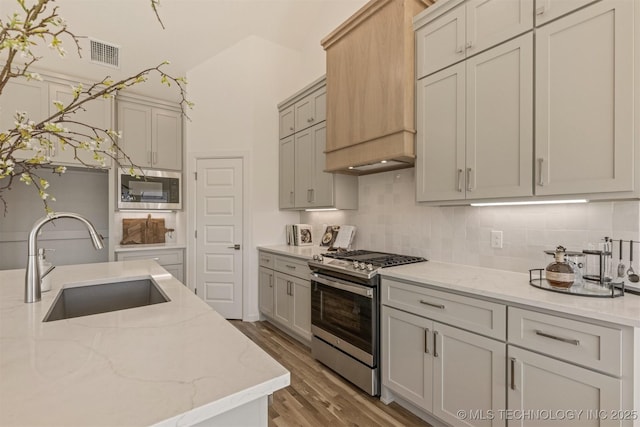 kitchen with stainless steel appliances, a sink, visible vents, decorative backsplash, and custom range hood