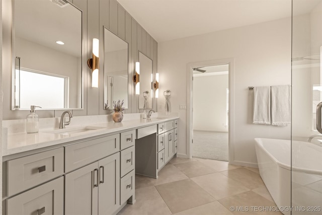 full bath featuring double vanity, tile patterned flooring, a freestanding bath, and a sink