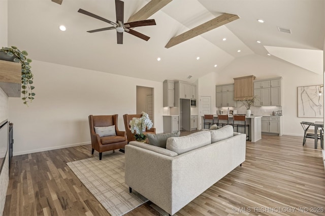 living room with high vaulted ceiling, wood finished floors, a ceiling fan, visible vents, and baseboards