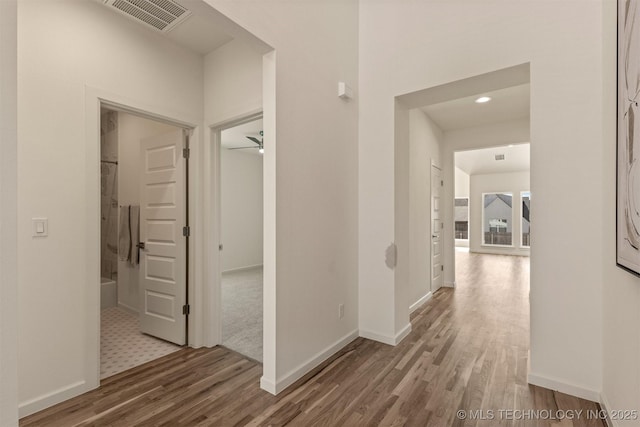 corridor featuring visible vents, baseboards, and wood finished floors