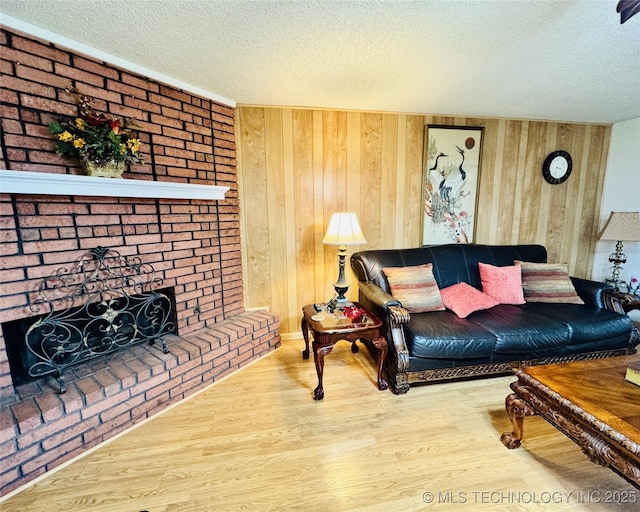 living area featuring a textured ceiling, wood finished floors, a fireplace, and wood walls