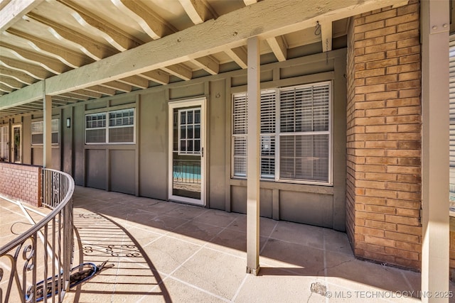 view of exterior entry featuring brick siding and a patio